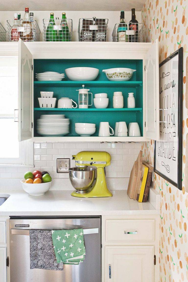 open cupboard kitchen with green background baskets up high on top yellow stand mixer on counter white dishes