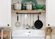 pan rack over white stove oven tile backsplash cabinetry kitchen green dishes spoon holder