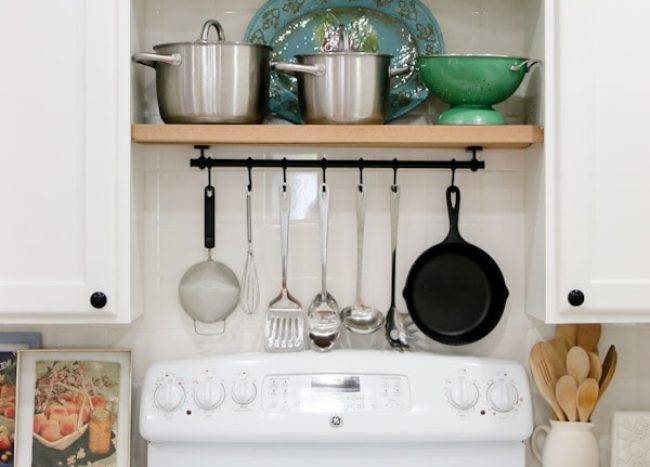 pan rack over white stove oven tile backsplash cabinetry kitchen green dishes spoon holder