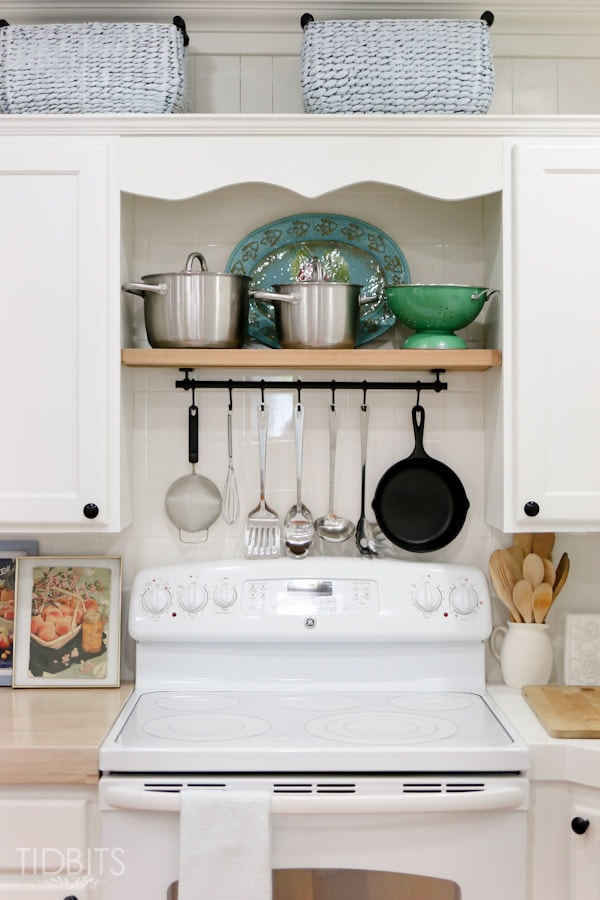pan rack over white stove oven tile backsplash cabinetry kitchen green dishes spoon holder