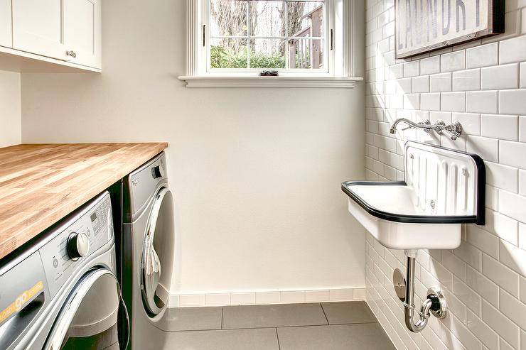 white subway tile wall mounted sink black and white butcher block counter top over stainless steel washer and dryer side by side