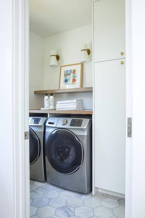 hexagon marble tile floor laundry room side by side washer and dryer stainless steel white gold wall sconce wood top counter folded towels