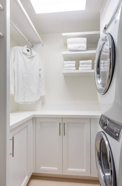 all white laundry room stacked washer and dryer clothes drying rod white towels skylight