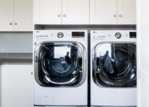 white shaker cabinets over front load washer and dryer pair wood tile floor