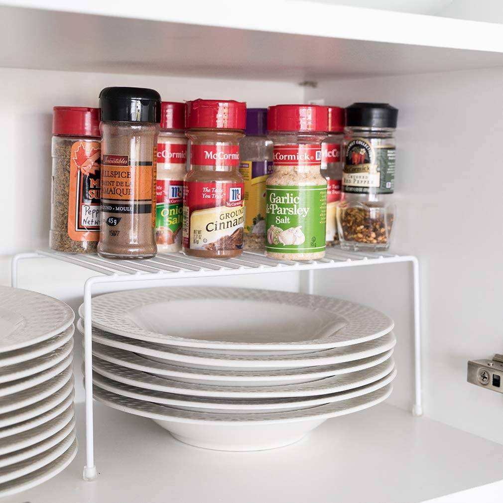 wire shelf riser inside cupboard white plates underneath spices on top