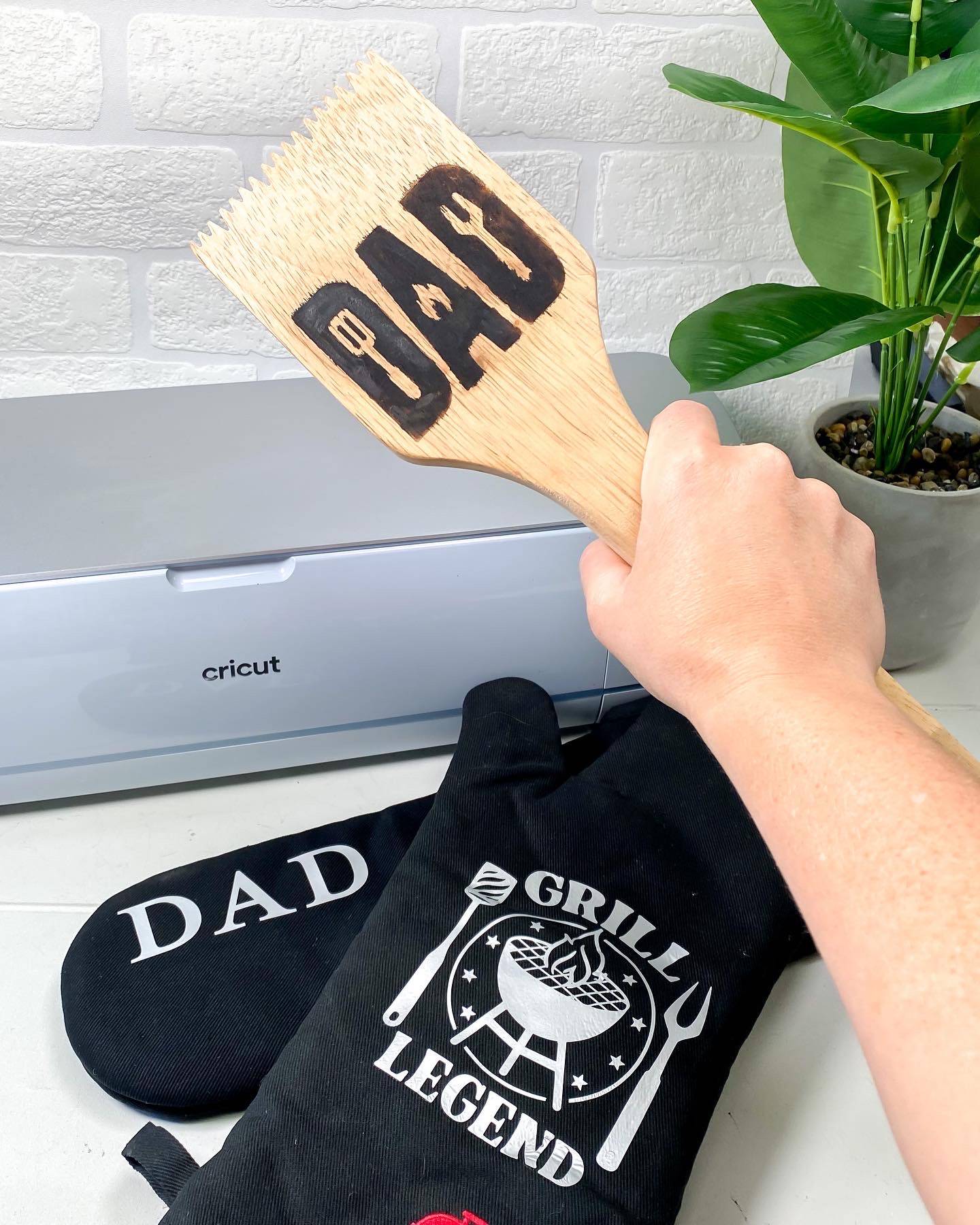 hand holding up wood bbq scraper dad fathers day gift ideas cricut maker 3 black oven mitts plant