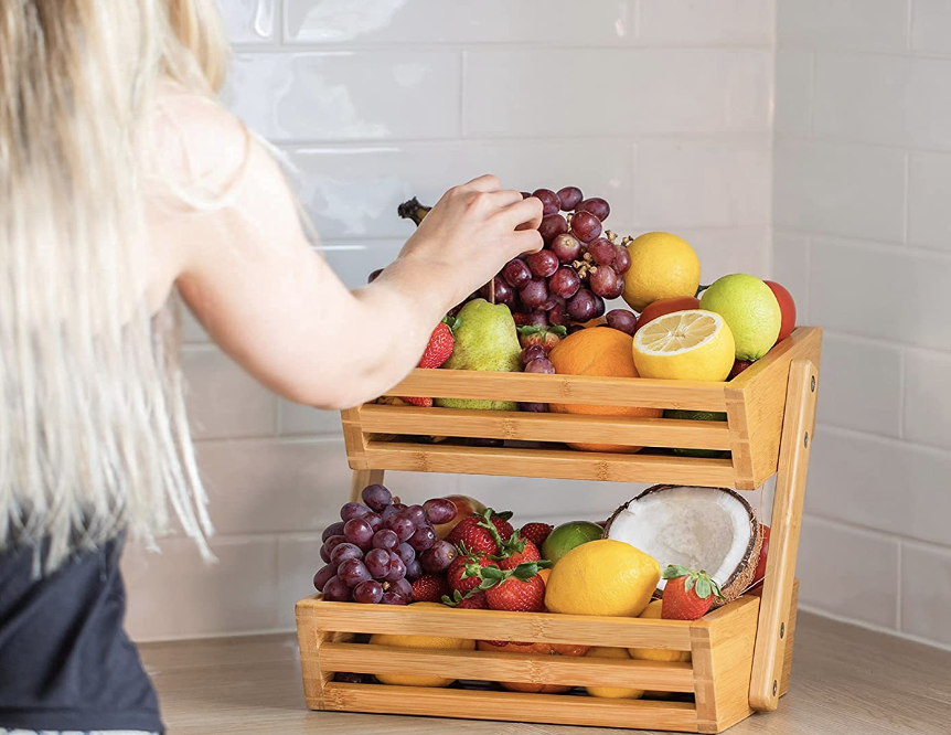 wood bamboo fruit holder full white subway tile background and woman reaching for grapes