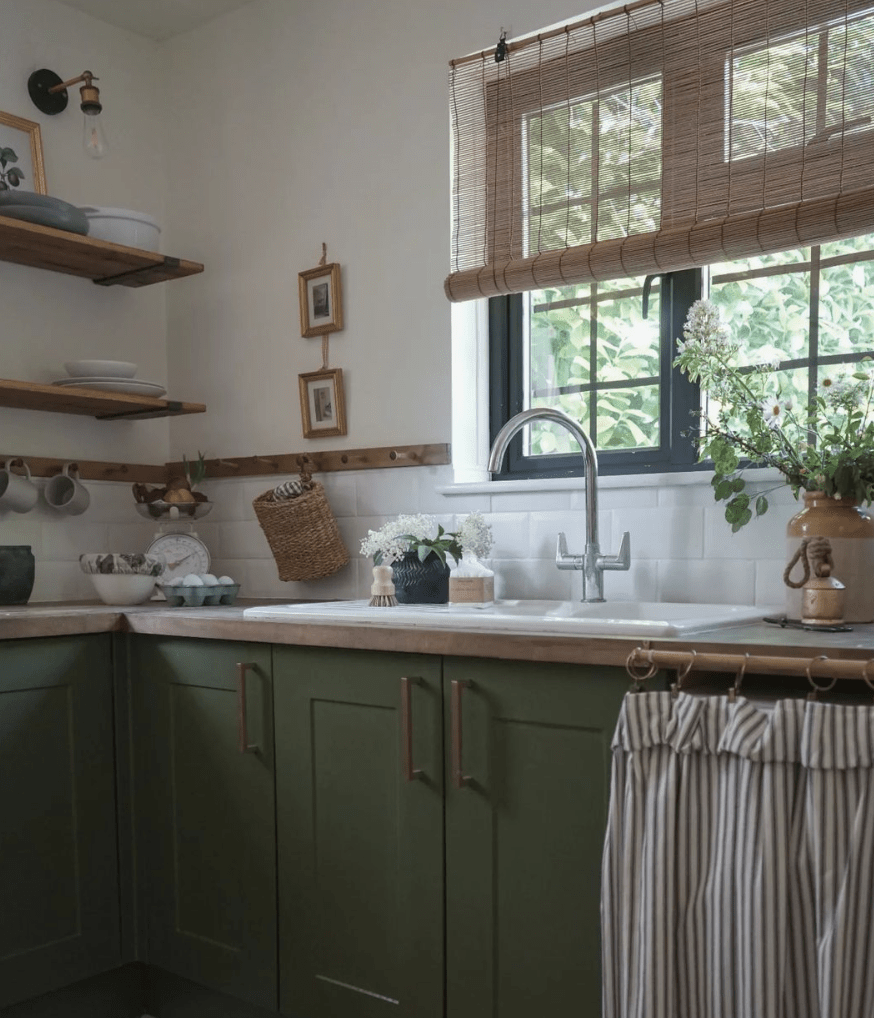 green kitchen cabinetry with white subway tile backsplash one window with black frames and bamboo shades open shelving