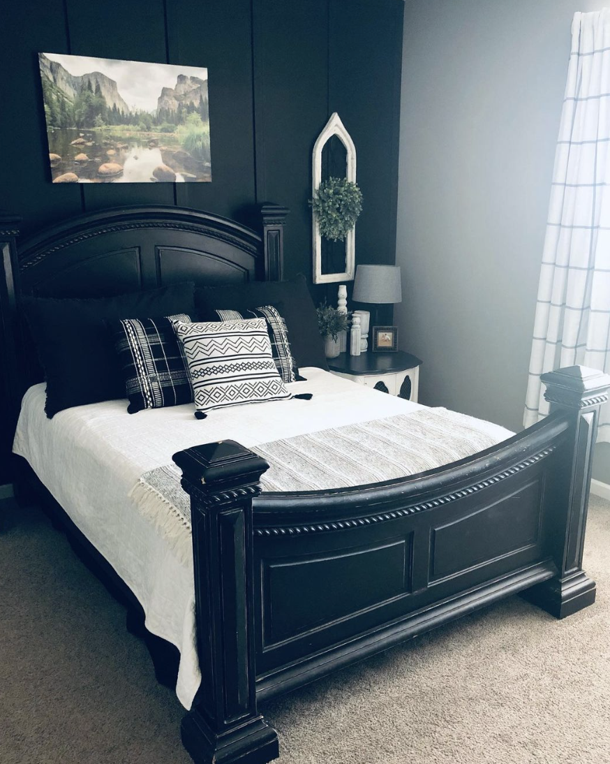 black bed in a black wall farmhouse bedroom white bedding and decorative throw pillows art hanging above bed