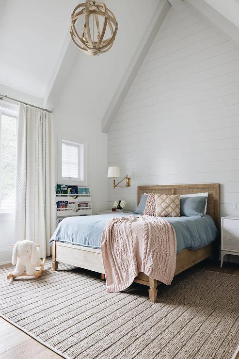 Kid's bedroom features a wood and cane headboard with blue and pink bedding atop a taupe rug.