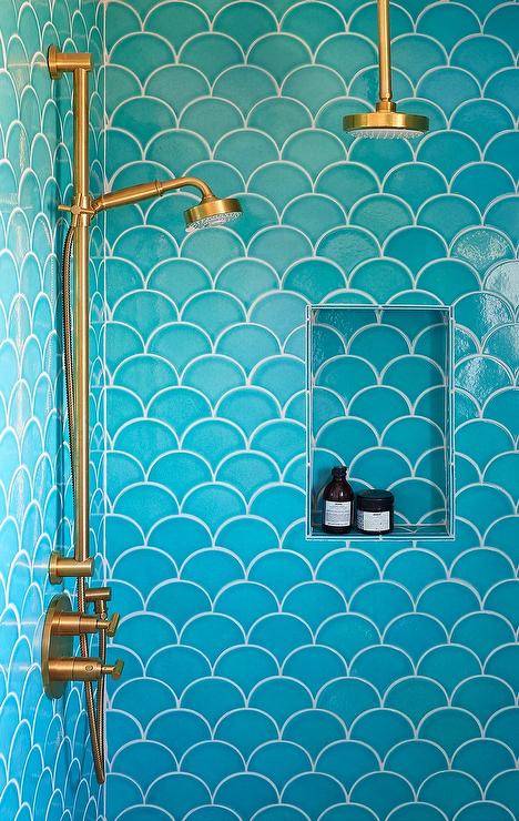 Shower features turquoise blue scale tiles, a blue scale tiled shower niche and a brass shower head.