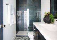 Black and blue geometric floor tiles black washstand with a white quartz countertop vanity mirror nickel towel bar mounted to a wall beside a walk-in shower finished with a glass partition and glossy blue stacked wall tiles