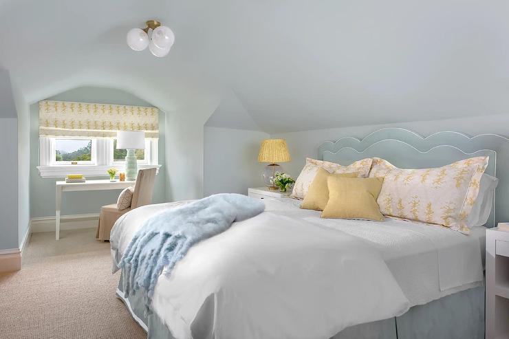 blue velvet scalloped headboard pleated bedskirt and finishing a bed dressed in white bedding topped with yellow pillows white nightstands lit by glass and brass globe lamps with yellow pleated shades