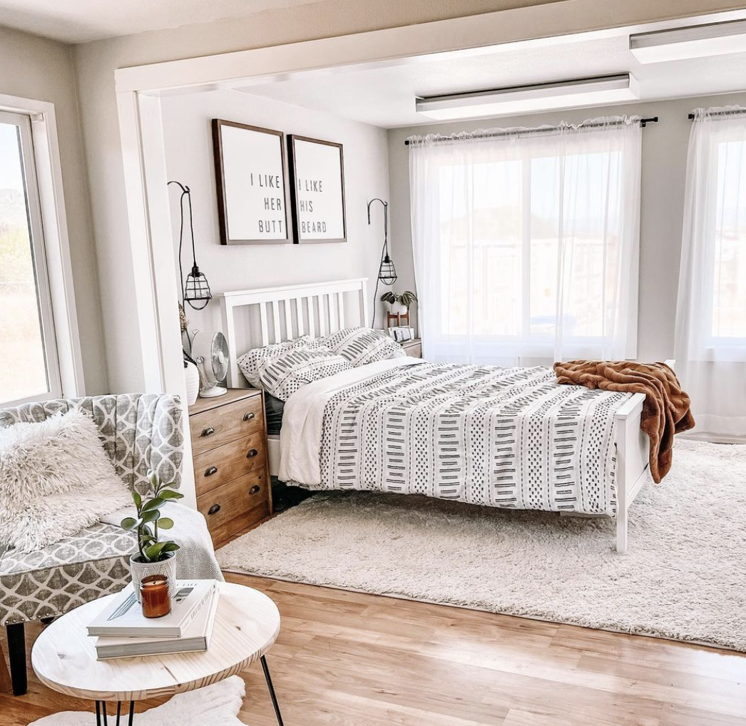 white modern farmhouse boho style bedroom bed geometric bedding accent chair and farmhouse signs hanging above bed