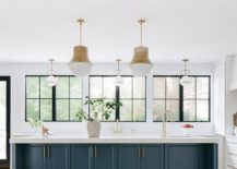 Pendants illuminate a peacock blue kitchen island finished with a sink and a brass gooseneck faucet
