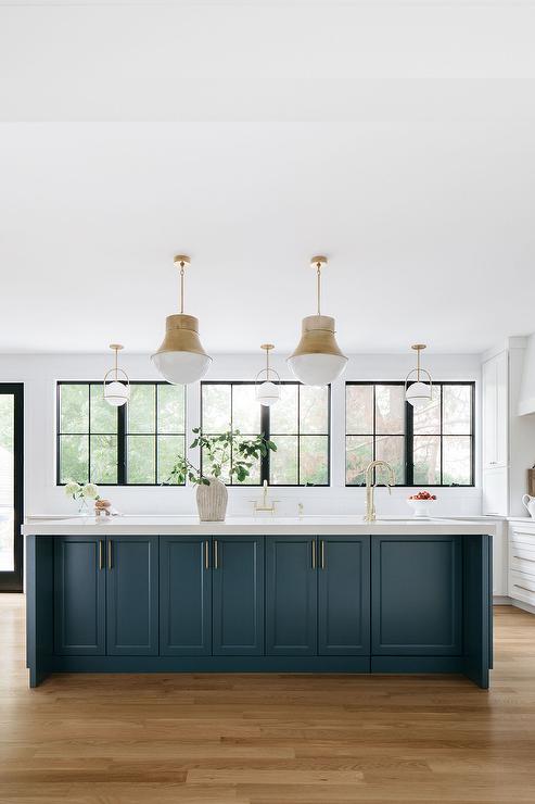 Pendants illuminate a peacock blue kitchen island finished with a sink and a brass gooseneck faucet