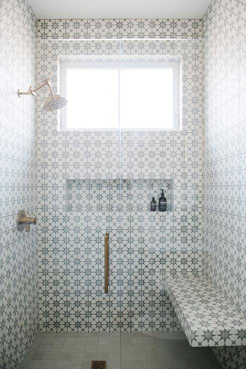 walk-in shower cement tiles floating tiled bench fixed over a gray grid floor and on a wall adjacent to a long tiled niche fixed beneath a window.