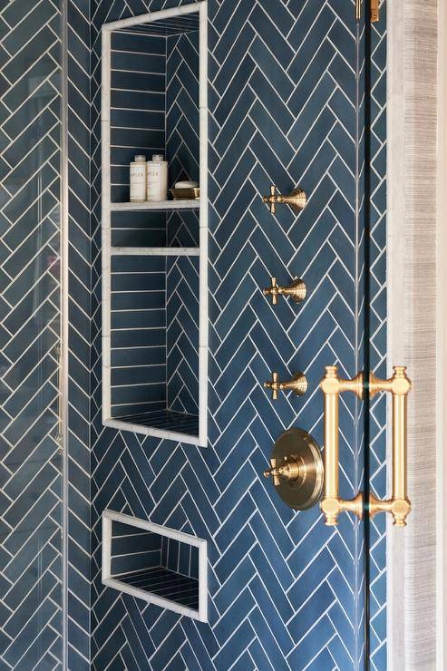 Blue tiled stacked shower niches are framed by blue herringbone shower wall tiles.