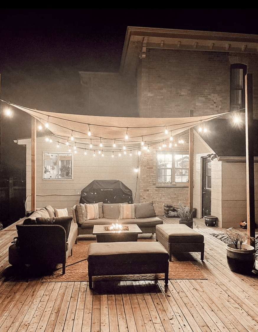 cloth canvas pergola with string lights outdoor couches backyard night time ottomans
