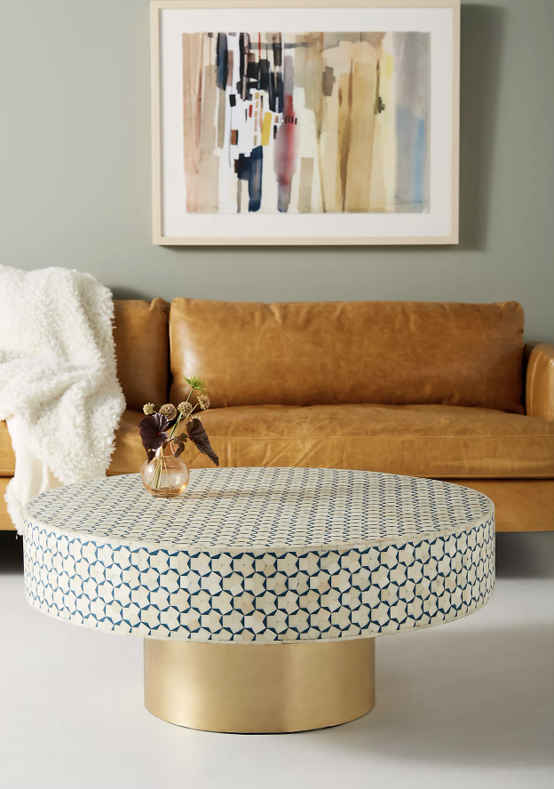 gold base coffee table with tile top brown leather couch in background