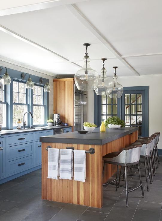 large wood island with blue cabinetry and glass pendants