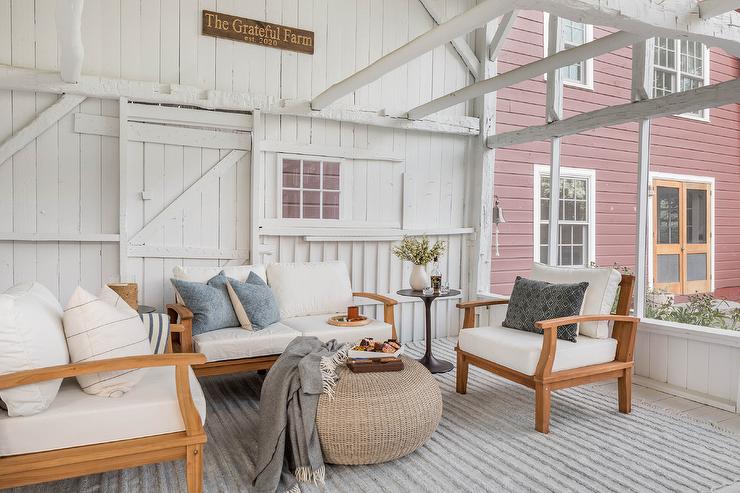 Country farmhouse porch with teak outdoor sofas and chairs.