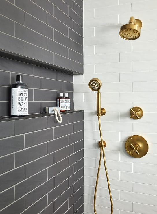 Dark gray glazed tiles walk-in shower with white grout and a brushed gold shower kit