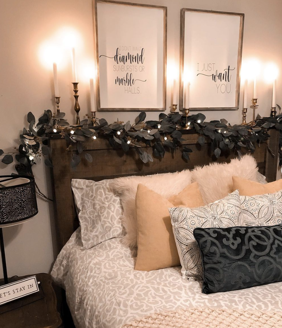 romantic farmhouse style bedroom with decorative throw pillows lit candles on gold candlesticks greenery
