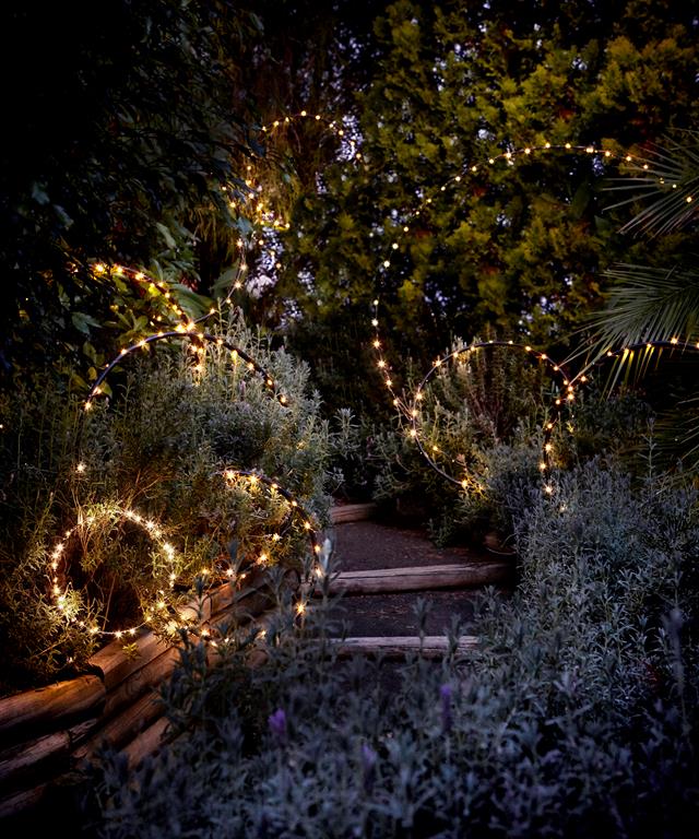 Fairy lights on hula hoops rings in garden path lit up at night