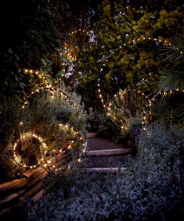 Fairy landscape lighting on hula hoops rings in garden path lit up at night