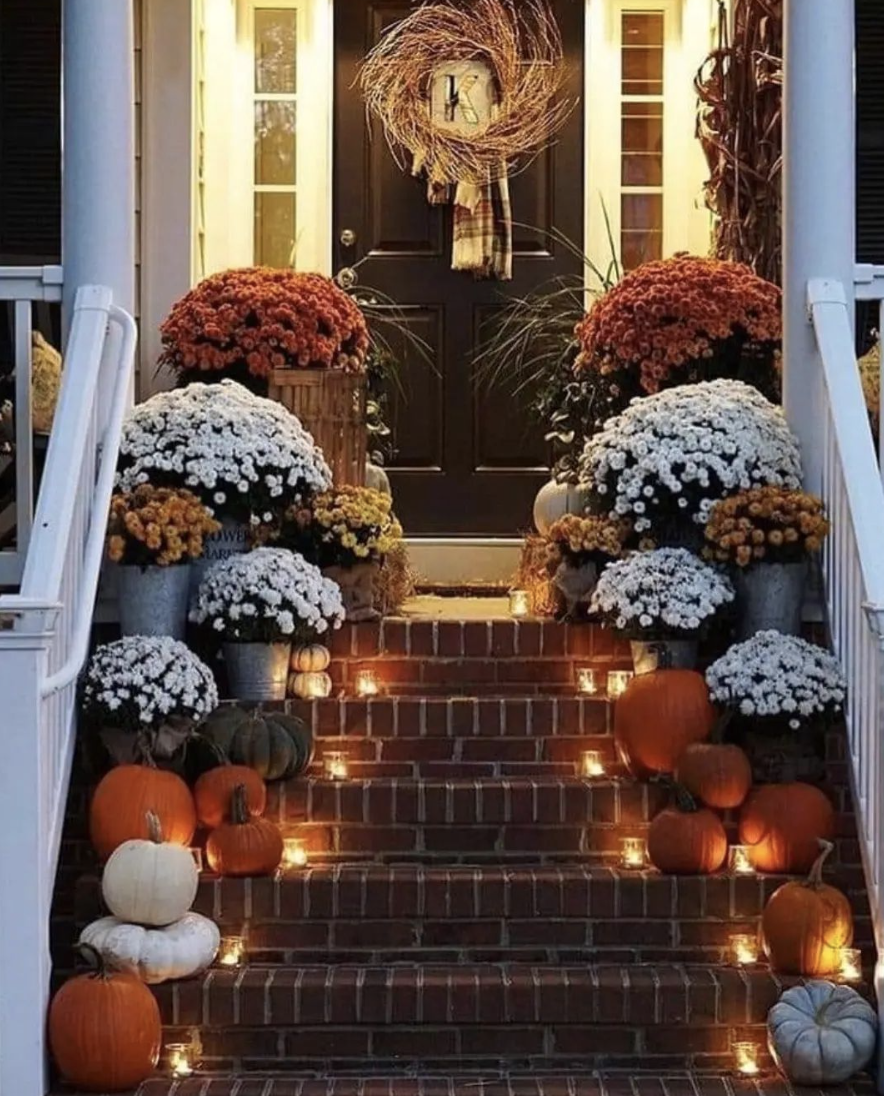 mums on fall porch up steps lit up rustic wreath on black door small pumpkins