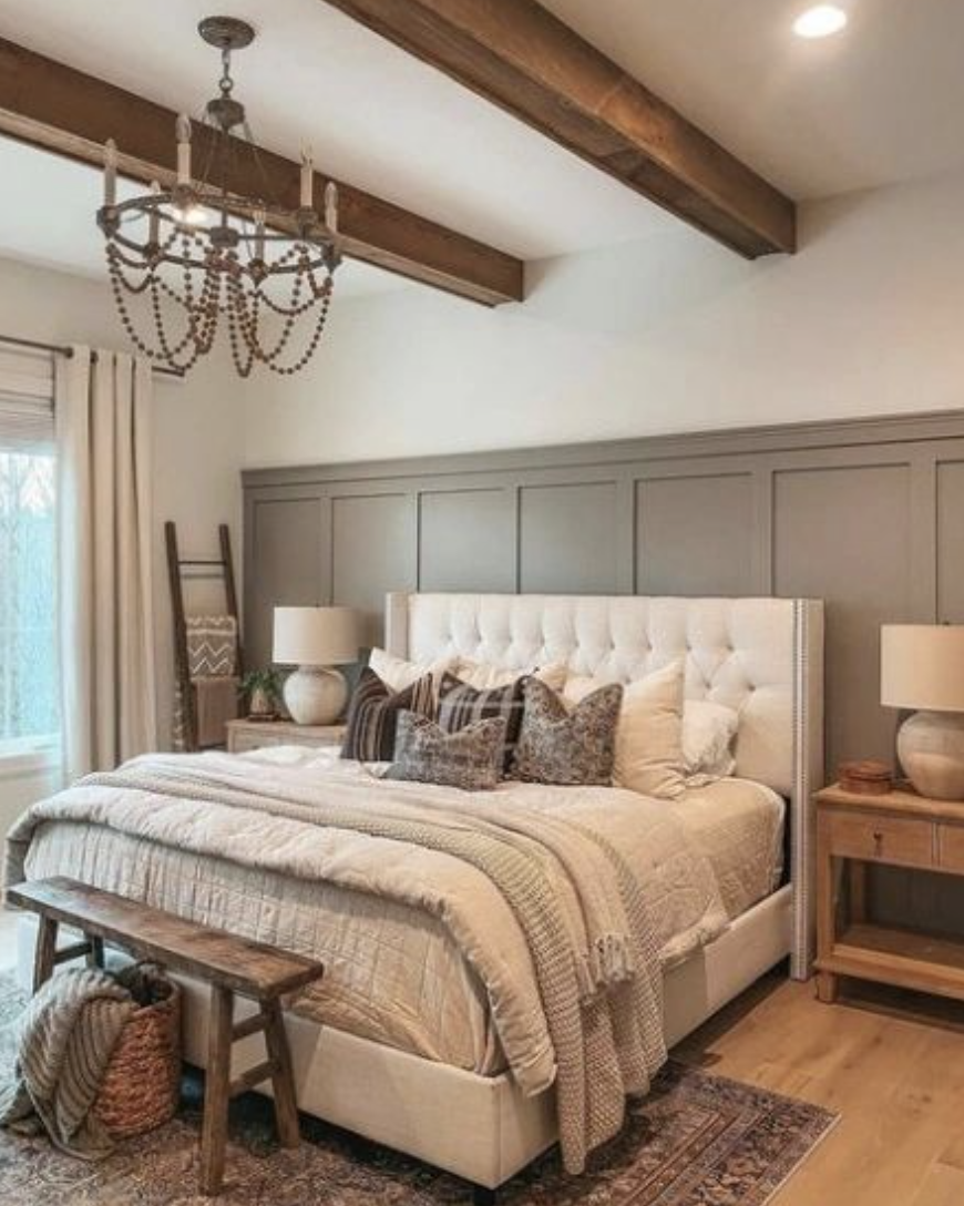 tufted white bed against sage green board and batted wall in farmhouse bedroom beaded chandelier wood primitive bench faux wood beams