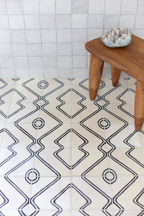 A teak stool sits in an expansive walk-in shower on ivory and black floor tiles and in front of gray glazed grid tiled walls