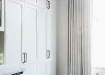floor to ceiling white canvas curtains on black curtain rod with white shaker cabinetry and dishwasher