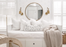 white day bed with drawers underneath for hidden storage white sailboat wallpaper with large round mirror gold wall sconce on either side