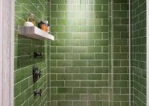 Walk-in shower green subway tile surround and ceiling accented with ceiling mounted square rain shower head over secondary shower head and marble floating shelf across from marble top shower bench
