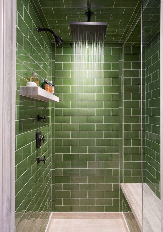 Walk-in shower green subway tile surround and ceiling accented with ceiling mounted square rain shower head over secondary shower head and marble floating shelf across from marble top shower bench