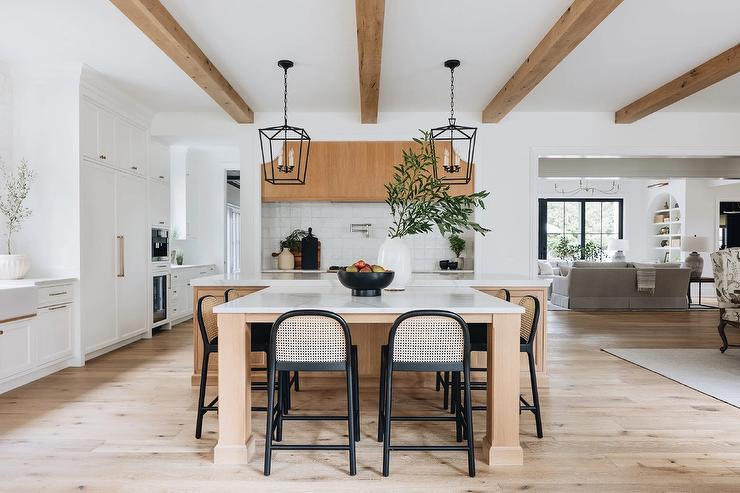 large island table in middle of kitchen with black stools faux wood beams on ceiling