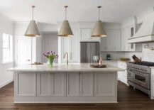 large beige island in middle of kitchen with three hanging pendants