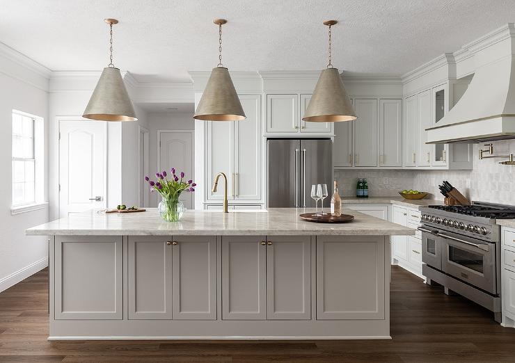 large beige island in middle of kitchen with three hanging pendants