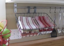 upcycled bicycle basket being used under kitchen cupboard with red dish towels inside