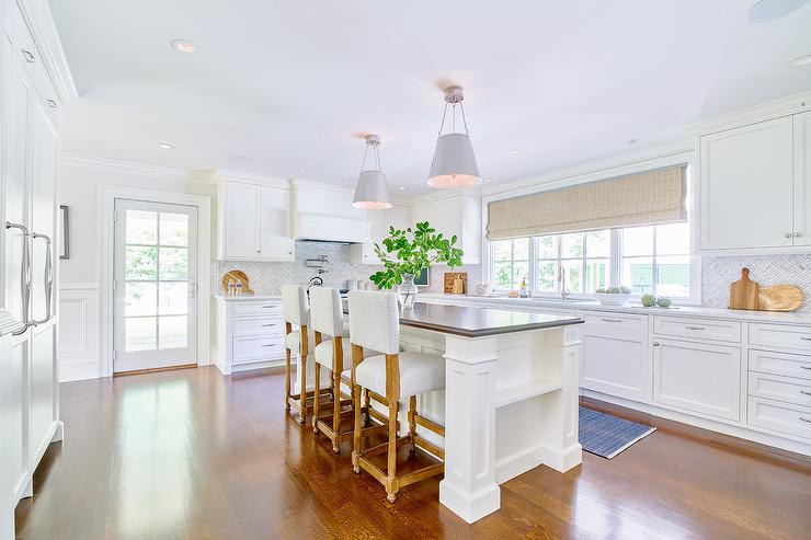 large white island in middle of kitchen with white stools and pendants