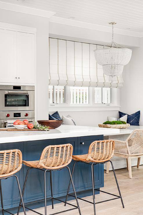 white and blue kitchen with rattan island stools white chandelier and large roman striped shade