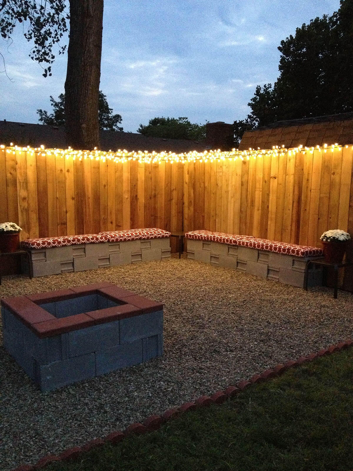 lit up fence in backyard at night with bench seating