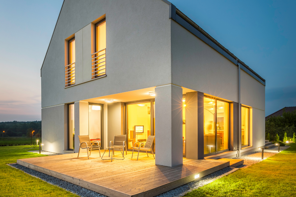 white house with landscape lighting and under porch yellow lighting.