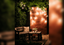 backyard at night lit up wall feature with string lights wood outdoor chair table