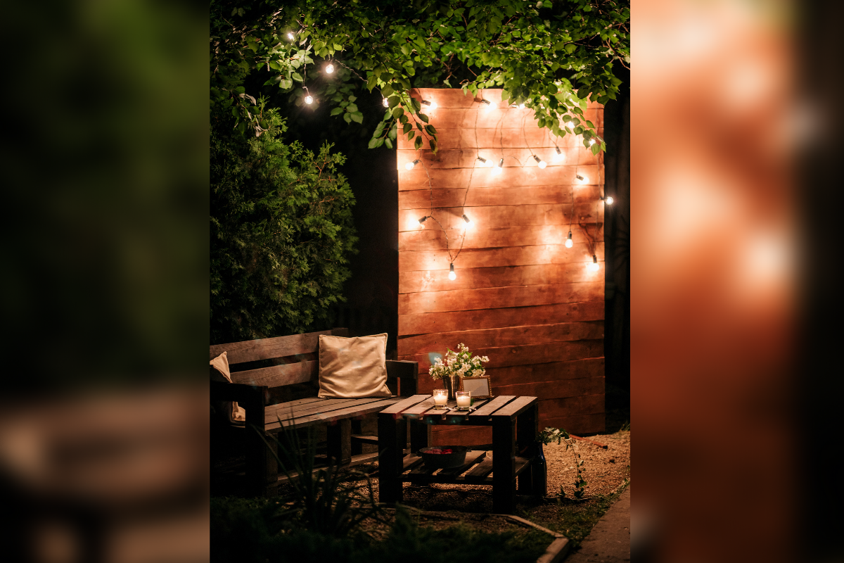 backyard at night lit up wall feature with string lights wood outdoor chair table