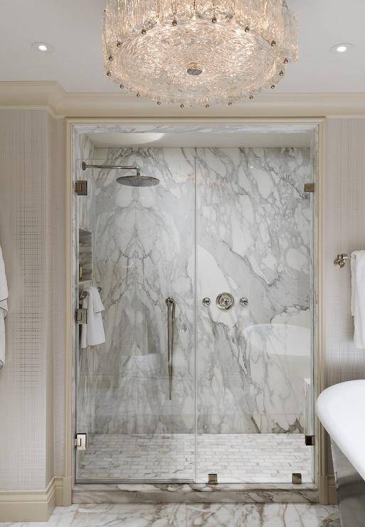 Marble subway tile floor in a walk in shower mixed with a marble slab shower wall adds a luxurious appeal to a master bathroom finished with a glass-enclosed door and nickel hardware