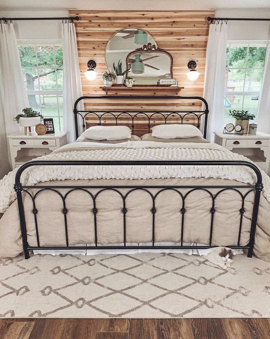 large farmhouse bedroom with bed accent wall black iron bed decorative wall sconce antique mirror two windows