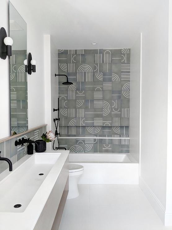 A drop in bathtub matched with a matte black shower kit is accented with white and gray modern mosaic wall tiles